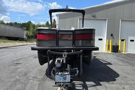 Slide: The Image of 2023 Barletta L25UCA pontoon boat parked outside a warehouse on a sunny day. - 2