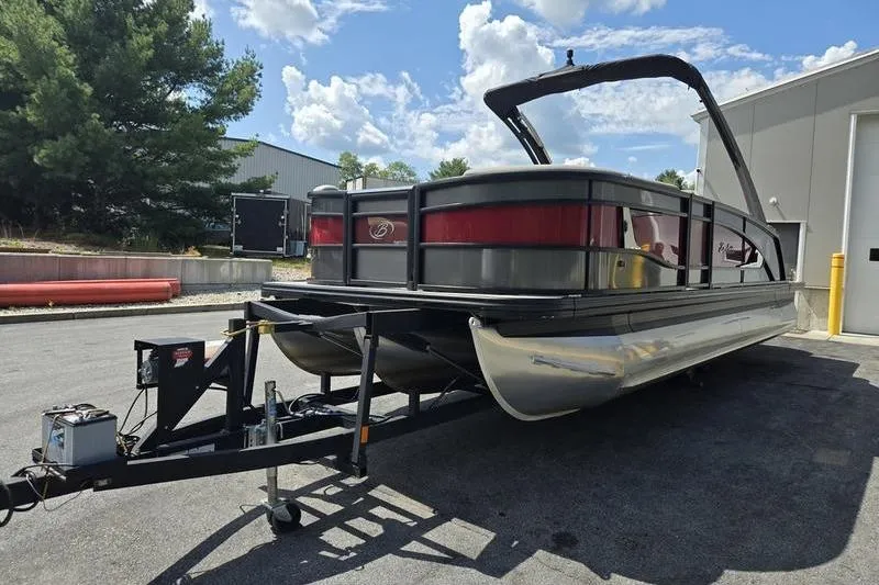 Slide: The Image of 2023 Barletta L25UCA pontoon boat on trailer, parked outdoors under a blue sky. - 22