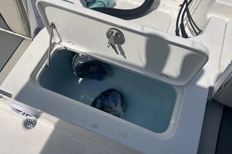 Slide: The Image of Open storage compartment on 2025 Key West 250 Bay Reef boat, containing bags. - 16