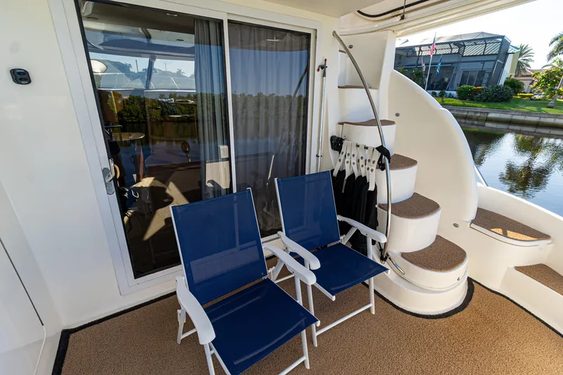 Slide: The Image of 2009 Meridian 391 Sedan yacht deck with blue chairs and spiral staircase by the water. - 5