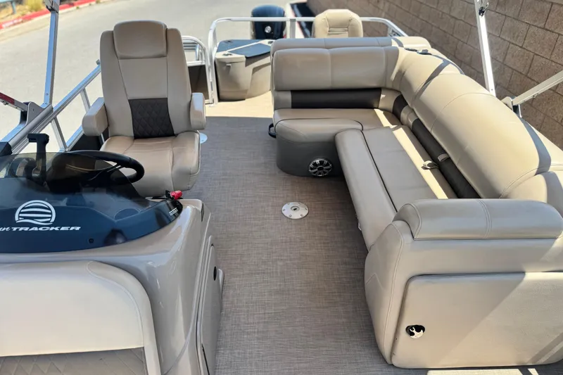 Slide: The Image of 2023 Sun Tracker SportFish 20 DLX pontoon boat interior with beige seating and steering console. - 12