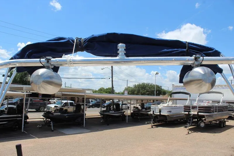 Slide: The Image of 2000 Chaparral 196 SSi boat with blue canopy, parked among other boats under a clear sky. - 14
