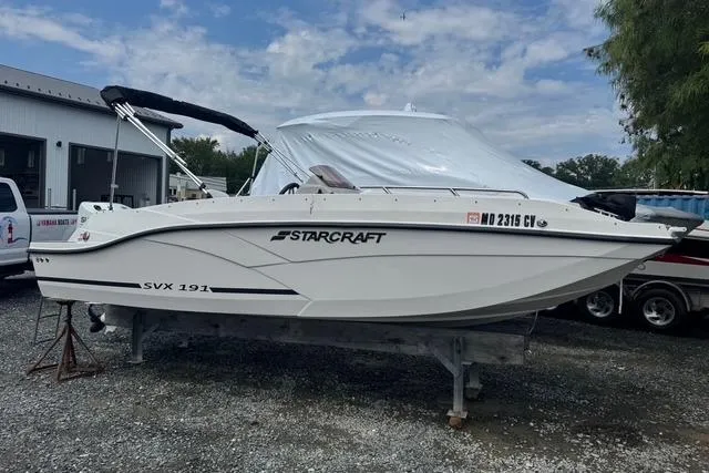 Slide: The Image of 2024 Starcraft SVX 191 OB boat on display, white exterior, parked outdoors. - 0
