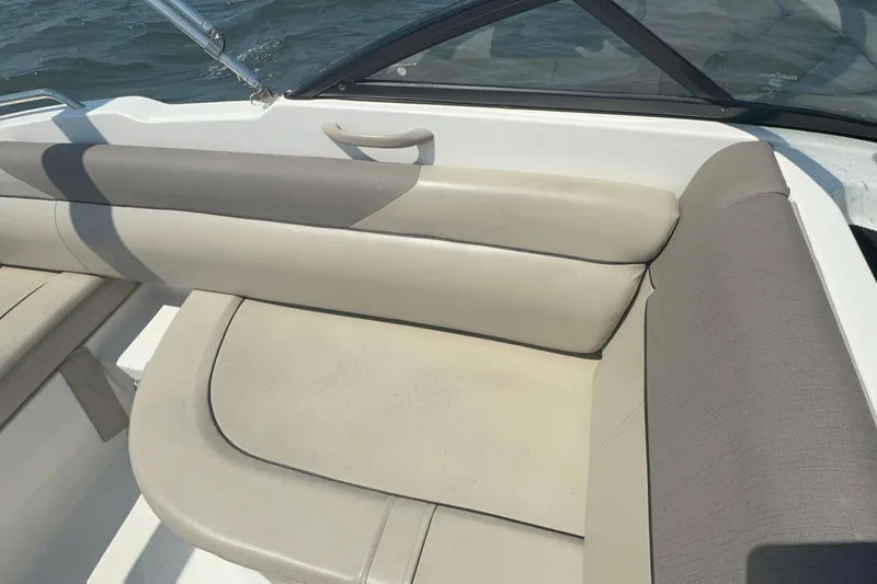 Slide: The Image of 2017 Bayliner 190 Deck Boat interior with beige seating and water view. - 11