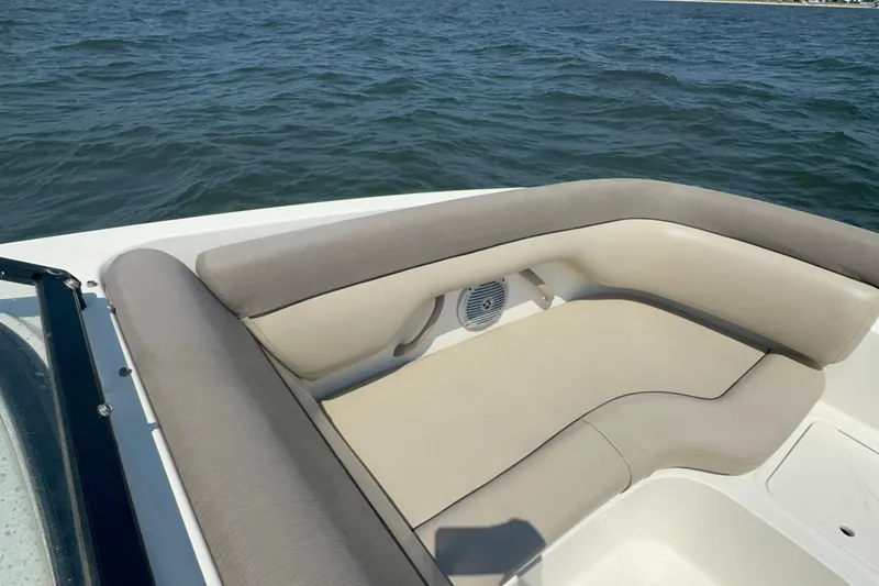 Slide: The Image of 2017 Bayliner 190 Deck Boat interior with beige seating, on calm water. - 17