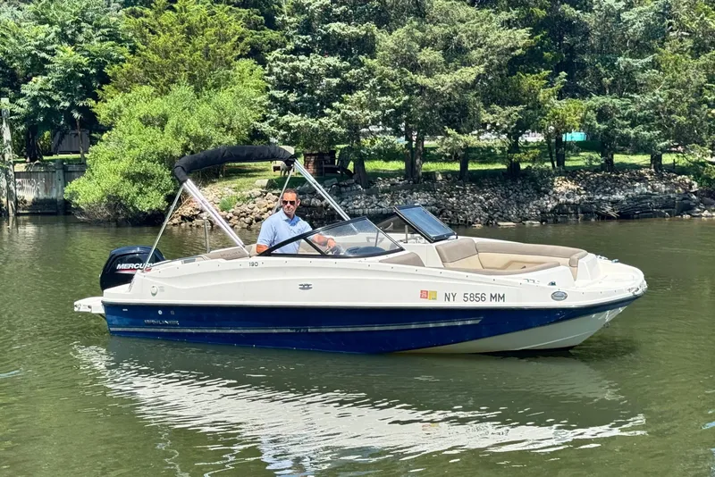 Slide: The Image of 2017 Bayliner 190 Deck Boat on calm water, surrounded by lush greenery. - 3