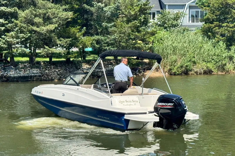 Slide: The Image of 2017 Bayliner 190 Deck Boat cruising on a scenic river with lush greenery. - 5