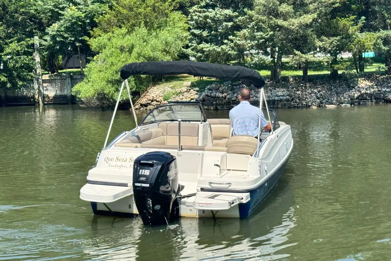 Slide: The Image of 2017 Bayliner 190 Deck Boat cruising on a calm river with lush greenery. - 7