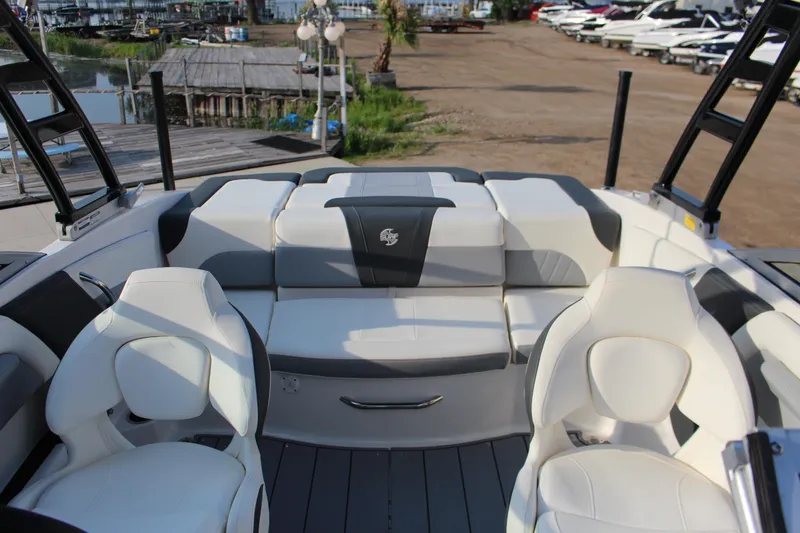 Slide: The Image of 2022 Chaparral 21 Surf boat interior with white and gray seating at a marina. - 10