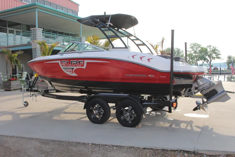 Slide: The Image of 2022 Chaparral 21 Surf boat on trailer, red and white design, parked outdoors. - 2