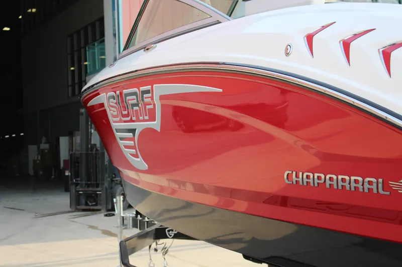 Slide: The Image of 2022 Chaparral 21 Surf boat with red and white design in a warehouse setting. - 3