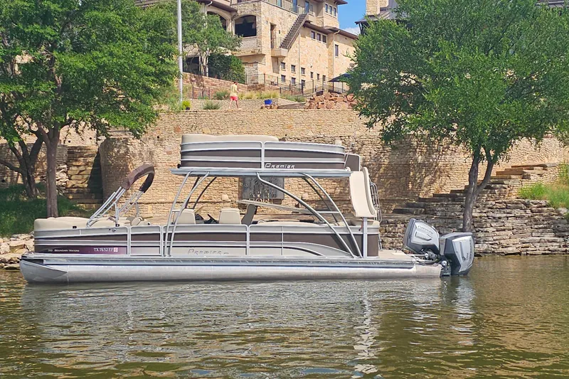 Slide: The Image of 2015 Premier 310 Escalante pontoon boat on a scenic lake near stone buildings. - 2