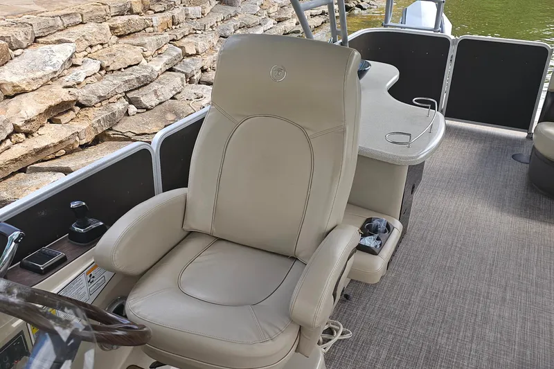 Slide: The Image of Captain's chair on 2015 Premier 310 Escalante pontoon boat, near stone wall and water. - 20