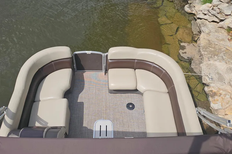 Slide: The Image of 2015 Premier 310 Escalante pontoon boat with beige seating, docked by rocky shore. - 9