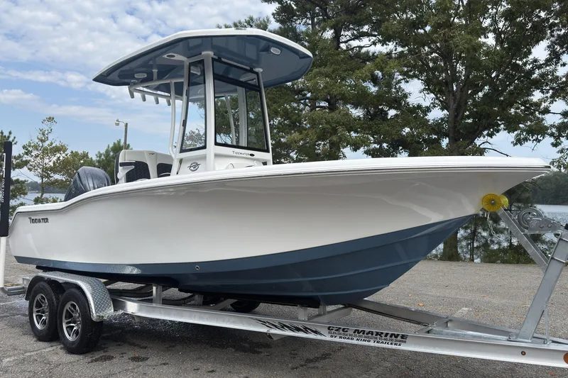 Slide: The Image of 2026 Tidewater 210 CC Adventure boat on trailer, parked near trees and water. - 3