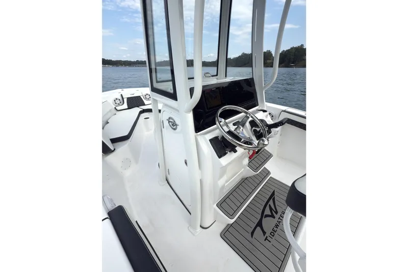 Slide: The Image of 2026 Tidewater 210 CC Adventure boat interior with steering wheel and console on a lake. - 5