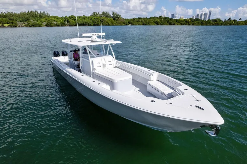 Slide: The Image of 2026 Contender 44 Fisharound boat on calm water, clear sky, lush shoreline. - 19