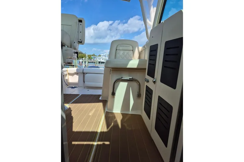 Slide: The Image of 2018 Grady-White Express 330 boat interior with seating and storage, under a clear blue sky. - 73