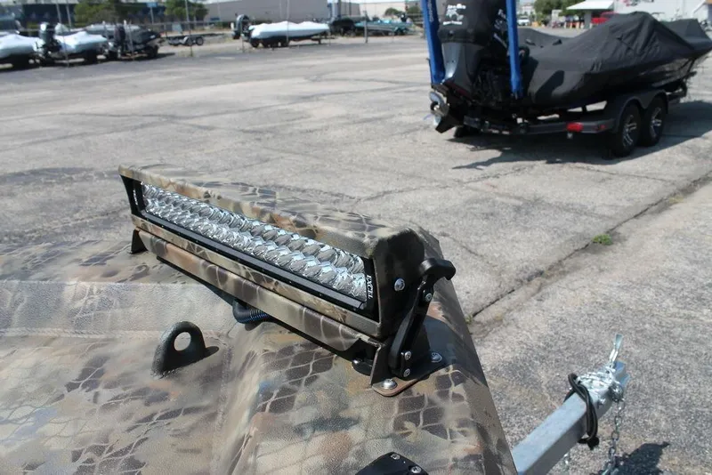 Slide: The Image of Camouflage-patterned Excel Shallow Water F4 boat with LED light bar, parked on a trailer. - 7