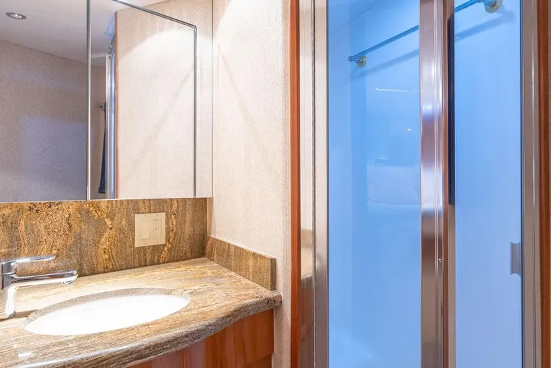 Slide: The Image of Luxurious bathroom in 2005 Hatteras Enclosed Bridge yacht with granite countertop and glass shower. - 25