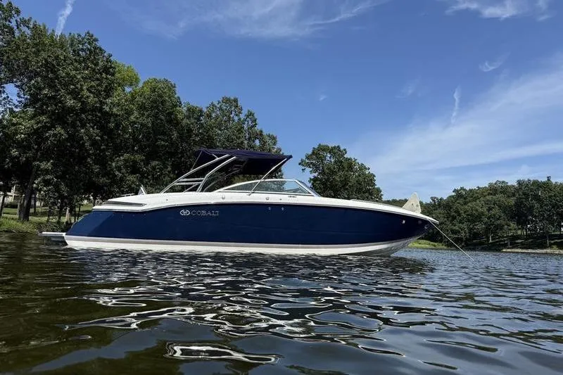 Slide: The Image of 2009 Cobalt 296 boat on water, clear sky, trees in background. - 10