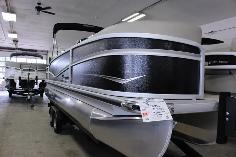 Slide: The Image of 2022 Premier 230 Explorer pontoon boat in showroom, black and silver design. - 15