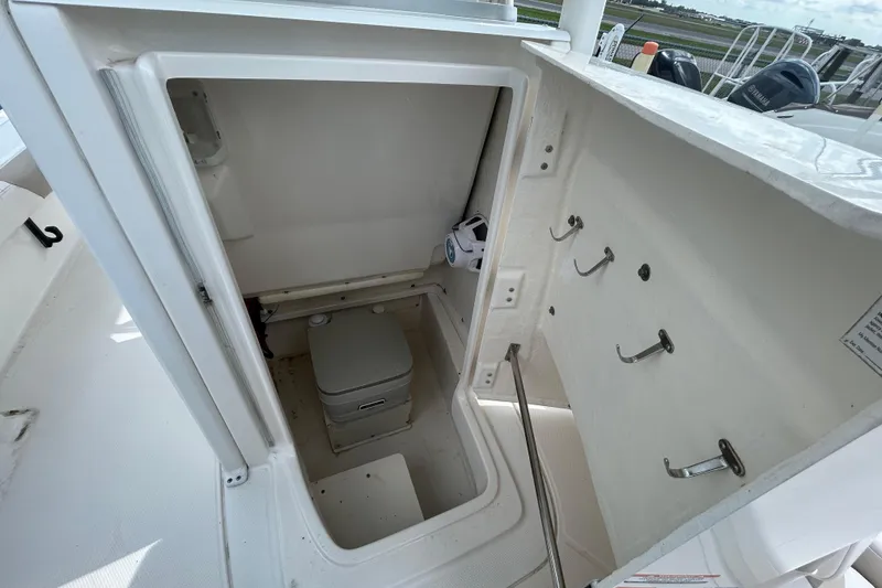 Slide: The Image of 2016 Robalo 246 Cayman boat interior with compact marine toilet and storage hooks. - 16