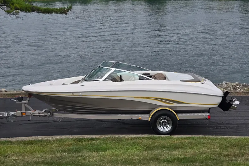 The Image of 2001 Tahoe Q5S I/O boat on trailer by a lake. - 0