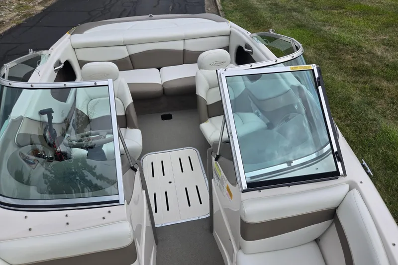 Slide: The Image of 2001 Tahoe Q5S I/O boat interior with white and beige seating, open windshield, and grassy background. - 19