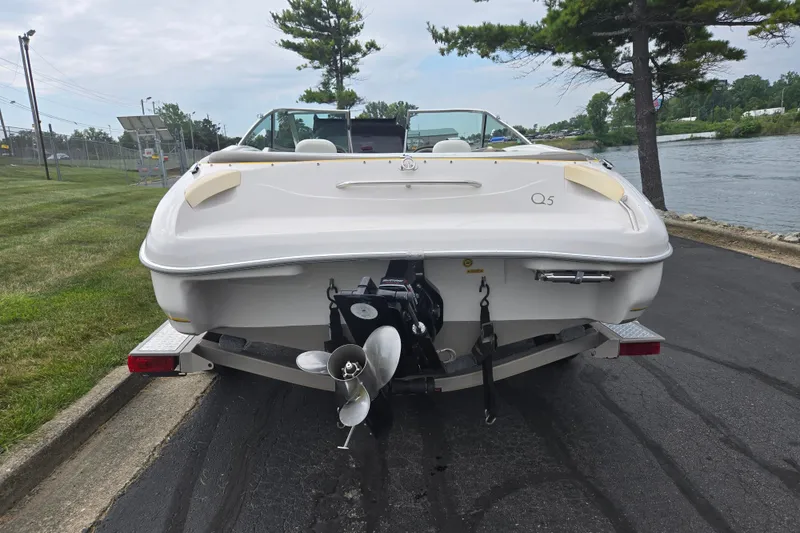 Slide: The Image of 2001 Tahoe Q5S I/O boat on trailer, parked near a riverbank. - 2