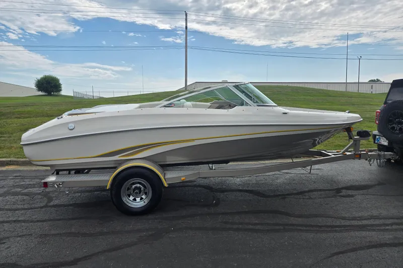 Slide: The Image of 2001 Tahoe Q5S I/O boat on trailer, parked outdoors under a partly cloudy sky. - 4