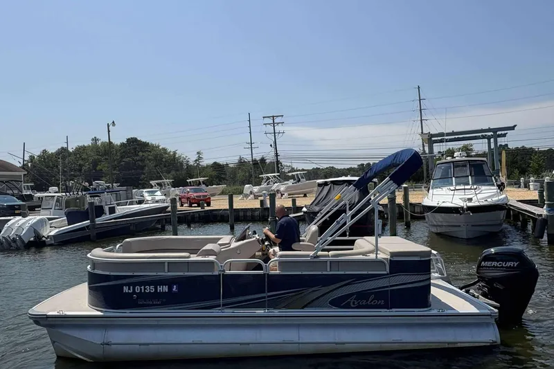 Slide: The Image of 2018 Avalon GS 2185 CR pontoon boat docked at marina with Mercury outboard motor. - 1
