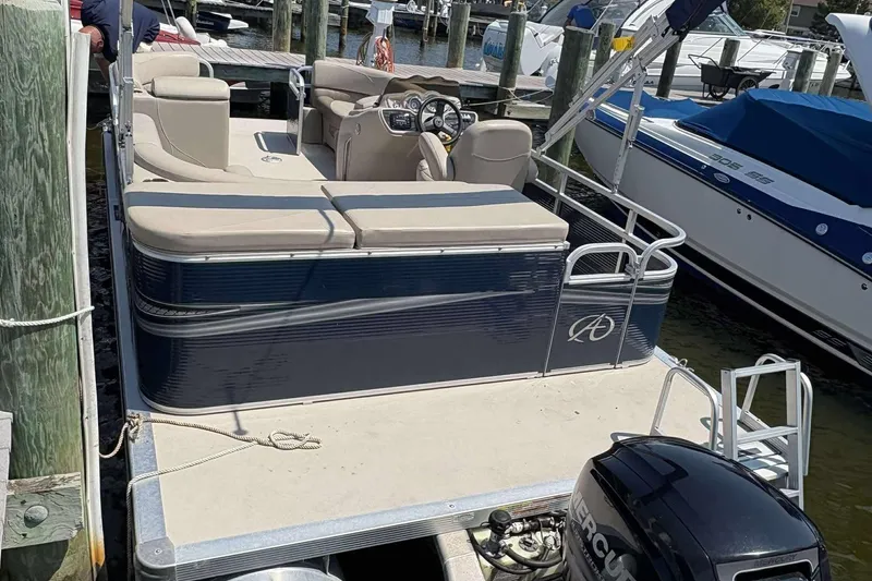 Slide: The Image of 2018 Avalon GS 2185 CR pontoon boat docked, featuring beige seating and a Mercury outboard motor. - 19