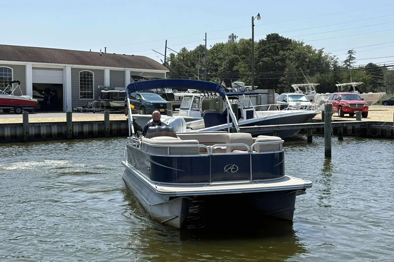 Slide: The Image of 2018 Avalon GS 2185 CR pontoon boat on water near marina with docked boats. - 6