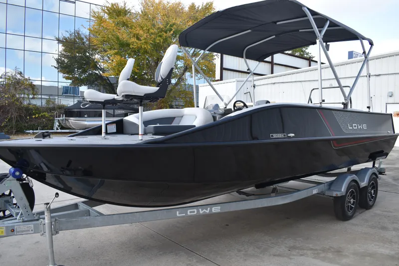 Slide: The Image of 2026 Lowe Sport Deck 224 boat on trailer, black exterior, dual seats, canopy, outdoor setting. - 11