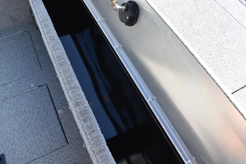 Slide: The Image of 2026 Lowe Sport Deck 224 boat storage compartment with carpeted interior and latch. - 22