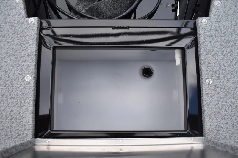 Slide: The Image of 2026 Lowe Sport Deck 224 boat storage compartment with drain, featuring carpeted edges. - 56