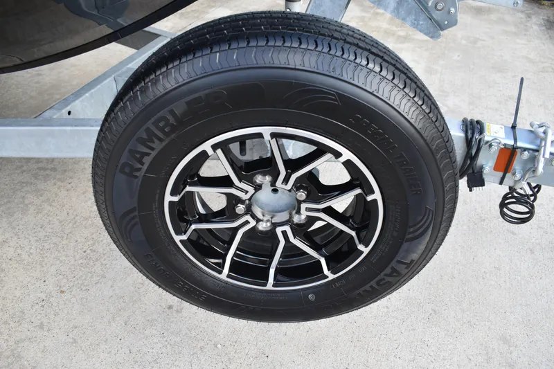 Slide: The Image of 2026 Lowe Sport Deck 224 trailer wheel with Rambler tire on concrete surface. - 6
