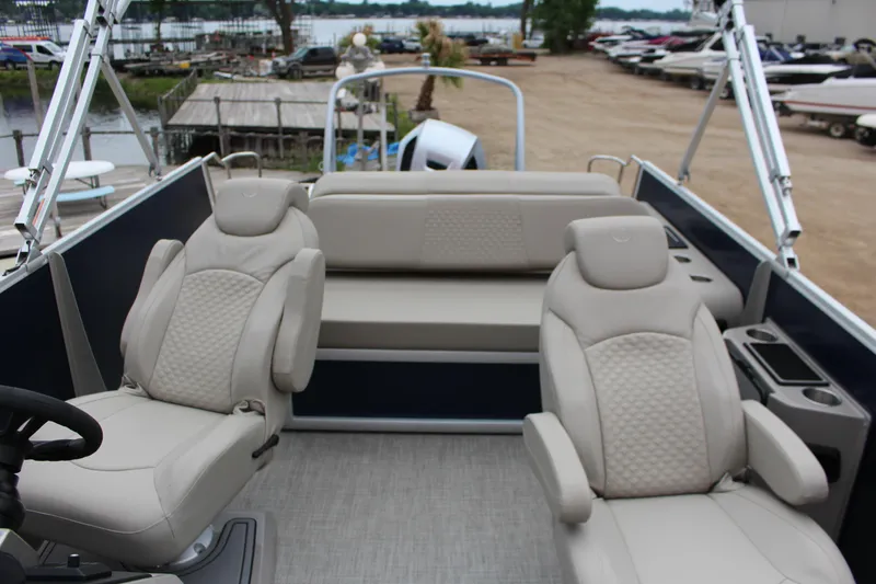 Slide: The Image of 2022 Premier Sunsation 230 pontoon boat interior with beige seating and lake view. - 6