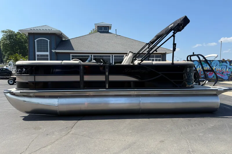 The Image of 2026 Bentley Pontoons Legacy 200 Navigator, black and beige, parked outdoors near a building. - 0