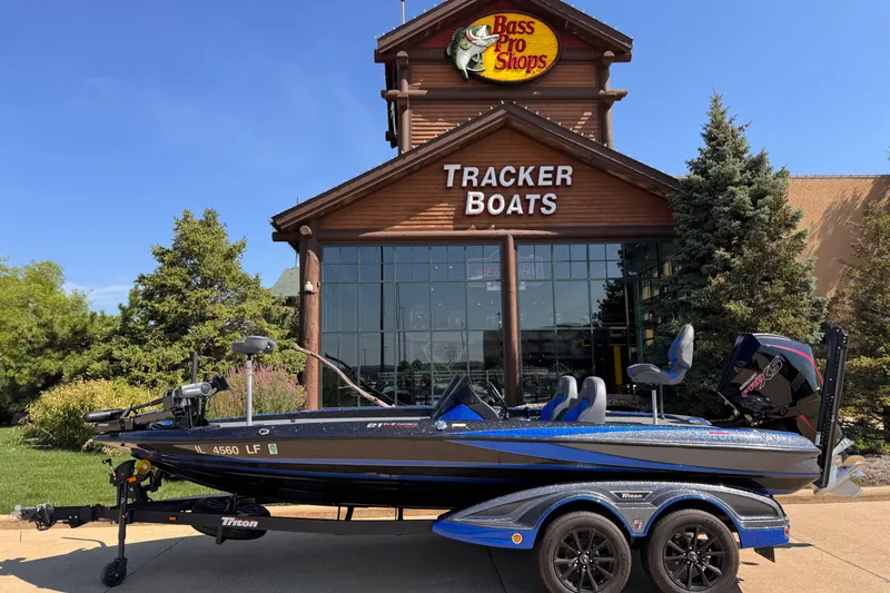 Slide: The Image of 2023 Triton 21TRXP boat displayed outside Bass Pro Shops Tracker Boats store. - 0