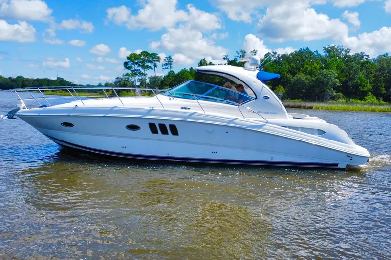 Slide: The Image of 2010 Sea Ray 390 Sundancer yacht cruising on a sunny day, surrounded by lush greenery. - 3