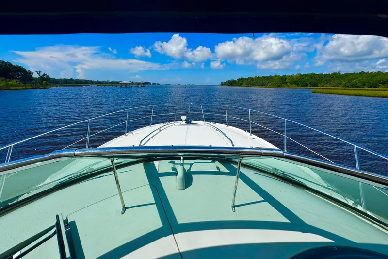 Slide: The Image of 2010 Sea Ray 390 Sundancer cruising on a serene river under a bright blue sky. - 8