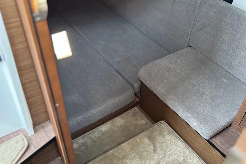 Slide: The Image of Interior cabin of 2022 Beneteau Antares 11 with gray seating and wooden accents. - 16