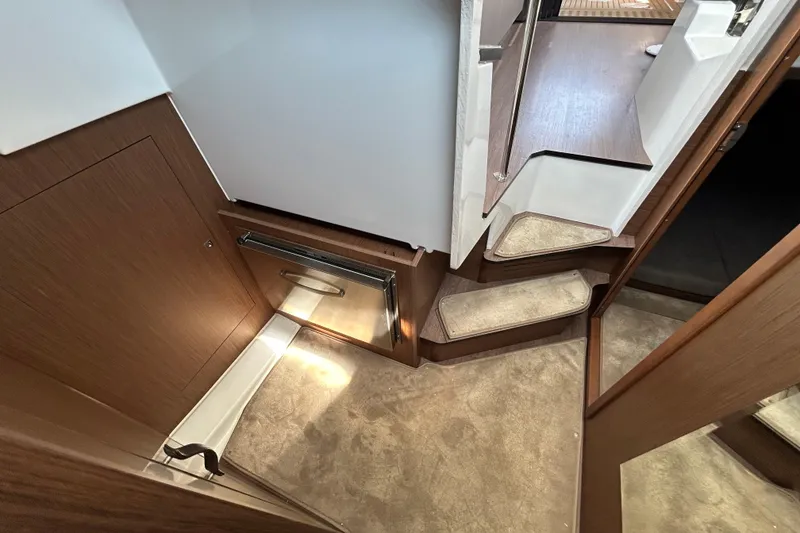 Slide: The Image of 2022 Beneteau Antares 11 interior with wooden cabinetry and carpeted steps. - 17