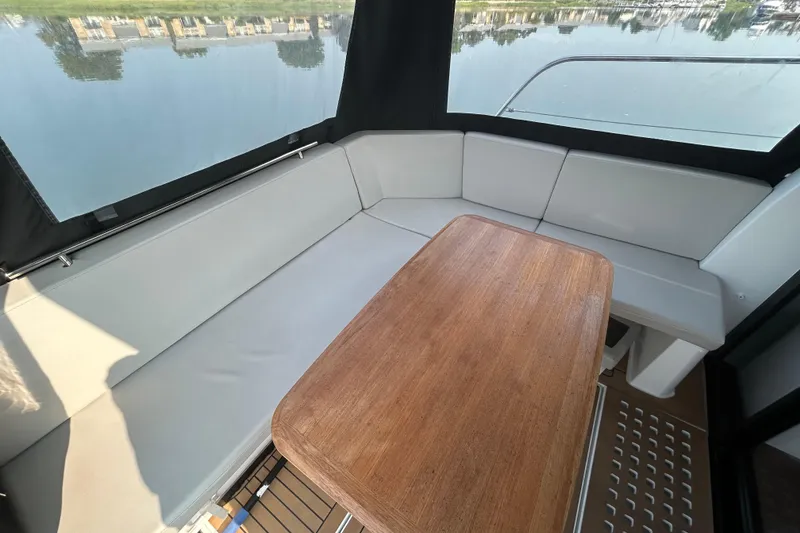 Slide: The Image of Interior of 2022 Beneteau Antares 11 with cushioned seating and wooden table. - 9