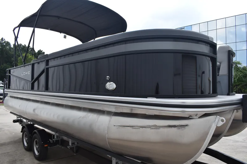 Slide: The Image of 2026 Lowe LF 232 pontoon boat on trailer, black exterior, parked outdoors. - 4