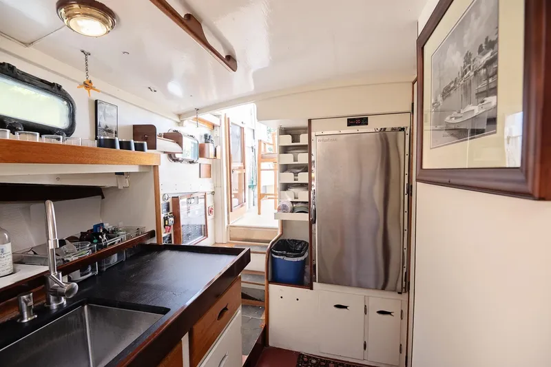Slide: The Image of 1972 Jarvis Newman Downeast boat interior with kitchen, stainless steel fridge, and wooden accents. - 23