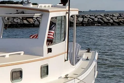 Slide: The Image of 1972 Jarvis Newman Downeast boat near rocky shoreline with American flag. - 7