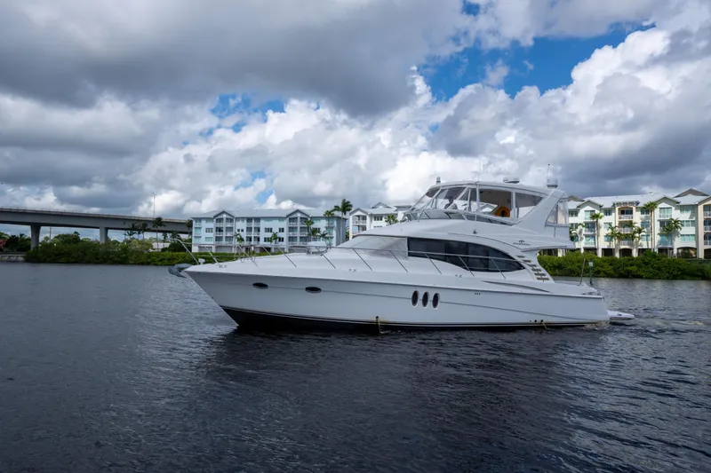 The Image of 2009 Silverton Oviation 52 yacht on water, cloudy sky, waterfront buildings in background. - 1